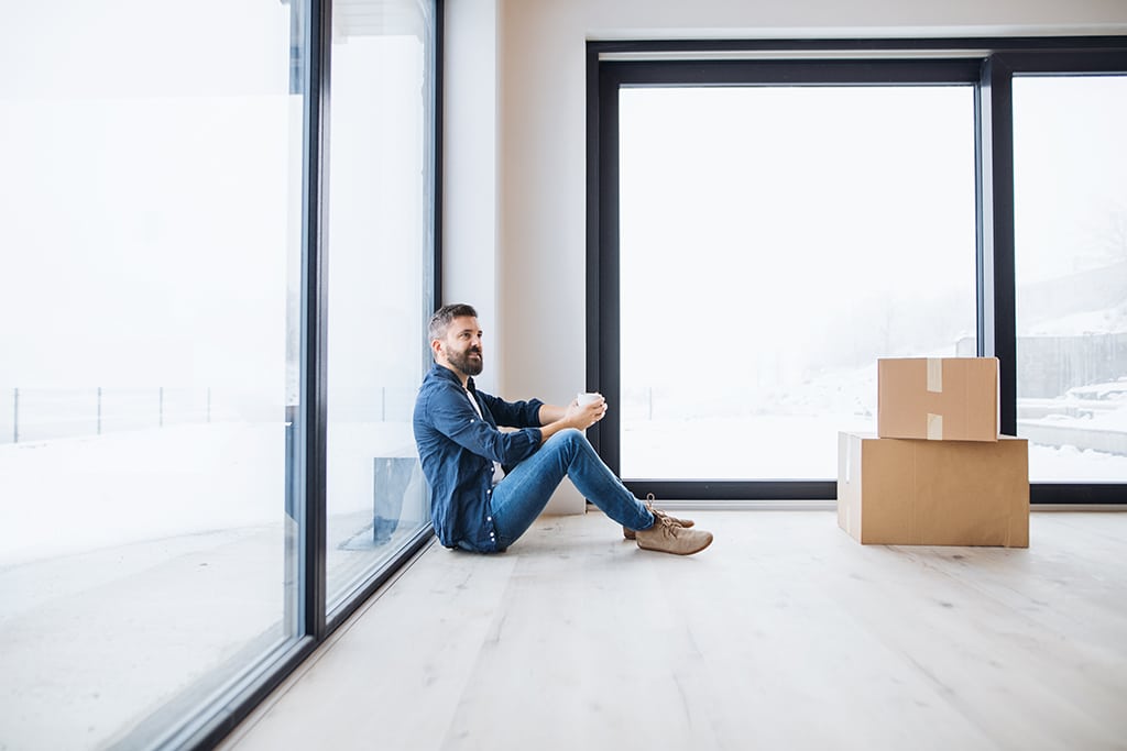A mature man with cardboard boxes sitting on the floor, furnishing new house. A new home concept. Copy space., new windows chicago