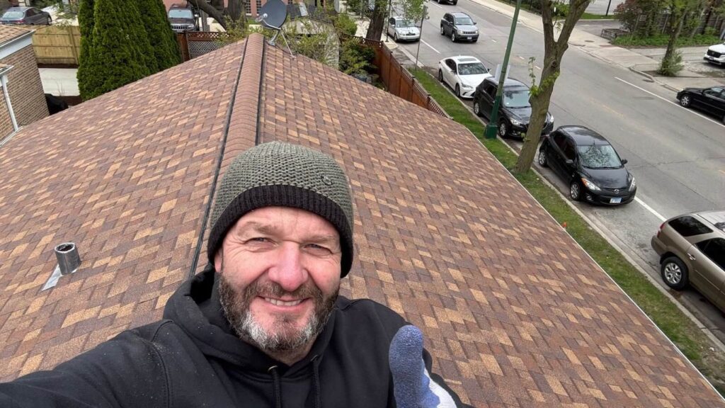 A person on a rooftop giving a thumbs up with cars on the street.