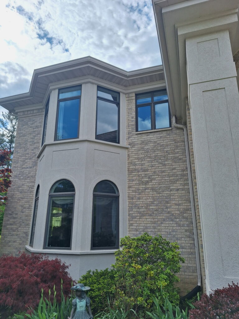 A large house with brick and stucco exterior, bay windows, and landscaping.