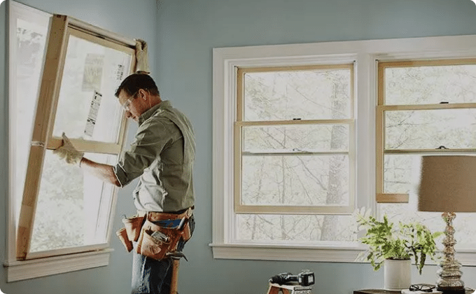 Installer fitting a single-hung window in a home